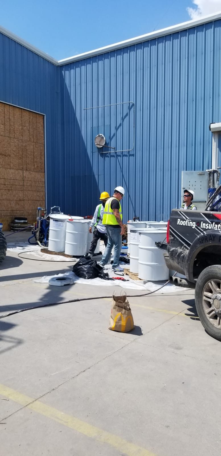 Crew staging coating drums and spray rig beside the Denver facility