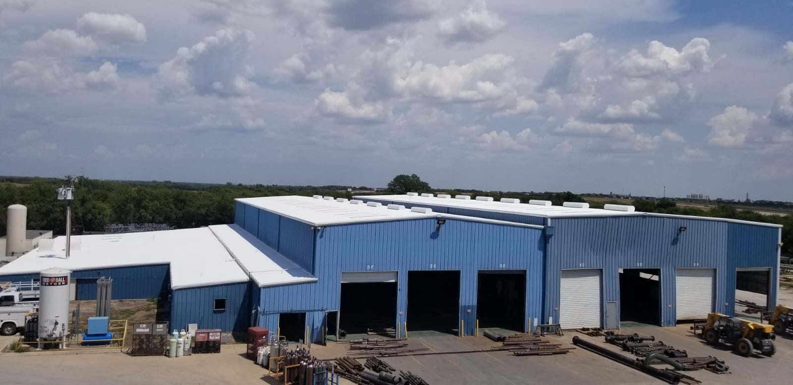 Finished white fluid applied roofs on a large blue metal industrial facility in Denver Colorado