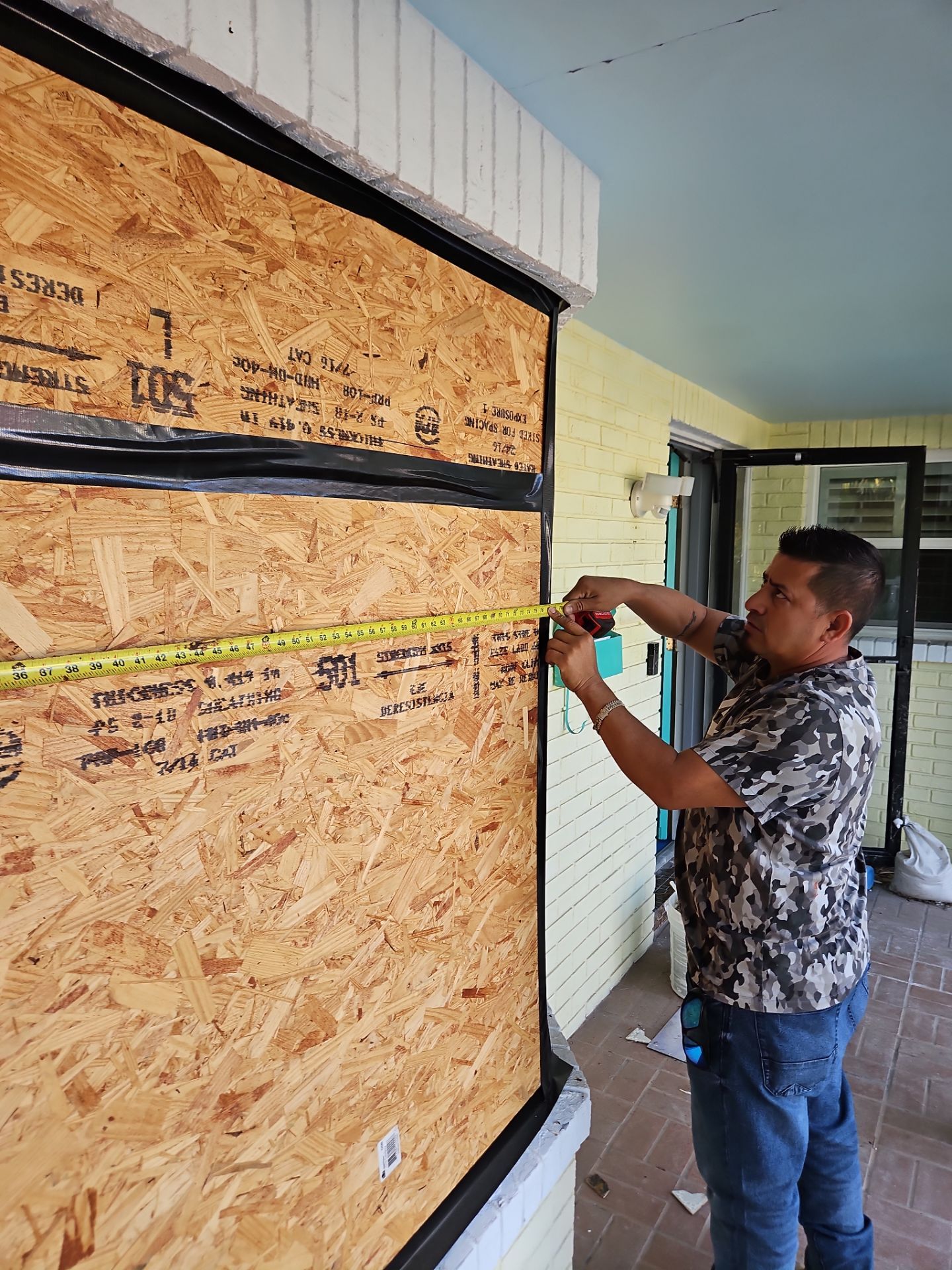 Crew member measuring a boarded opening during restoration