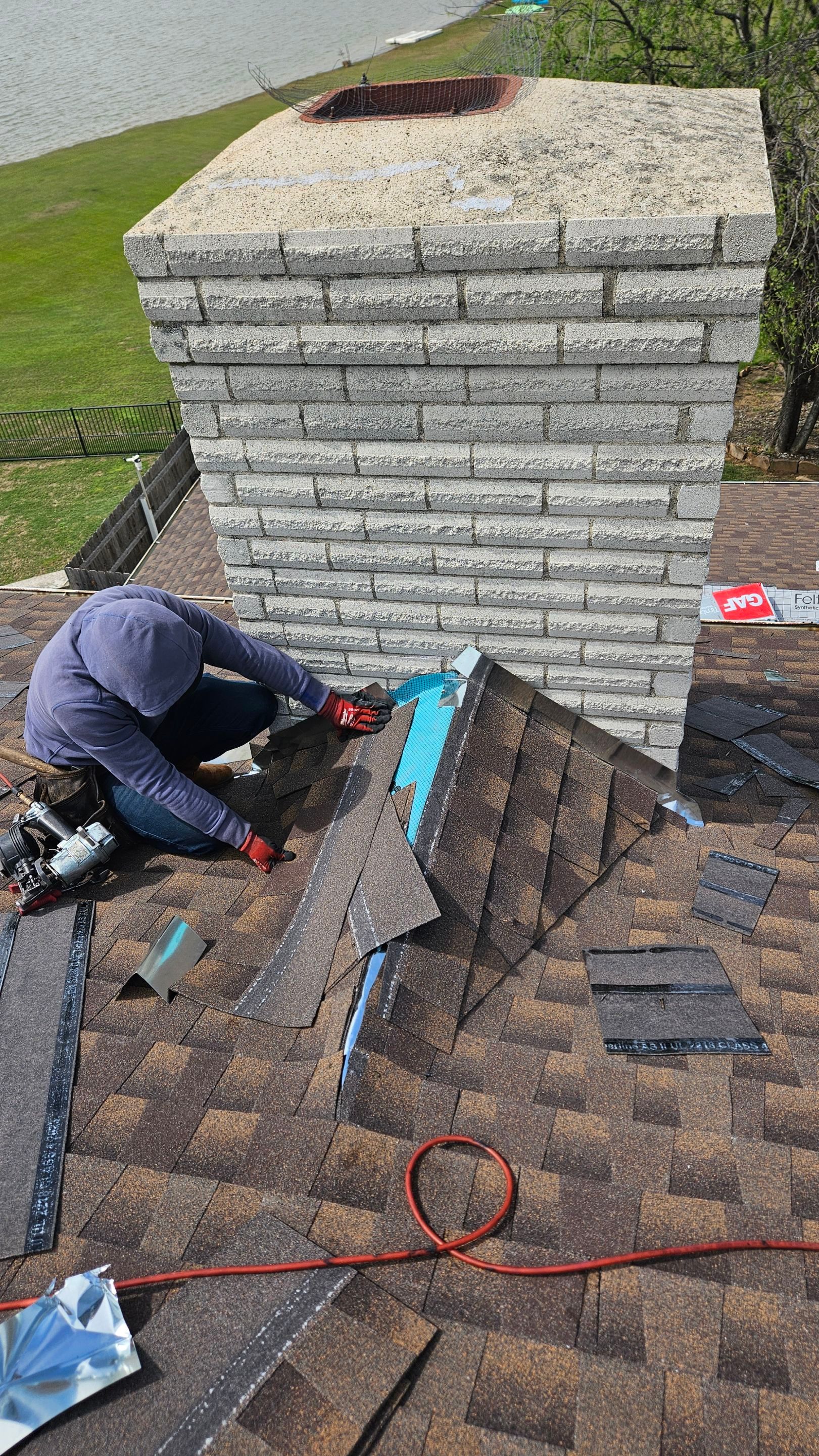Roof repair crew beside a stone chimney, Gold Coast Roofing and Solar