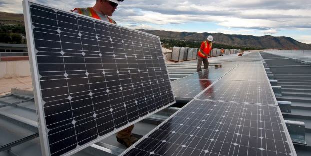 Workers installing solar panels on a commercial roof